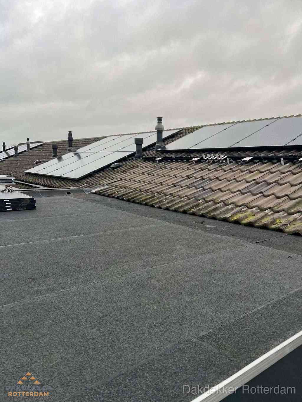 Plat dak inspectie met bitumen bedekking naast schuin pannendak in Rotterdam