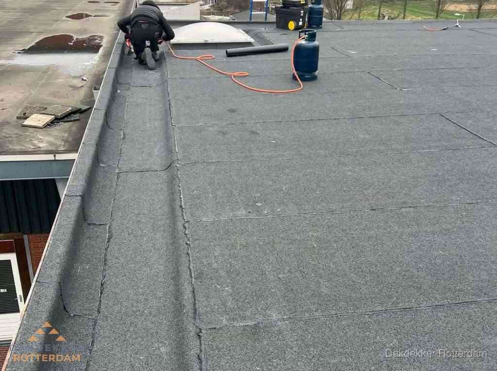 Dakdekker repareert bitumen dakbedekking op groot plat dak in Rotterdam